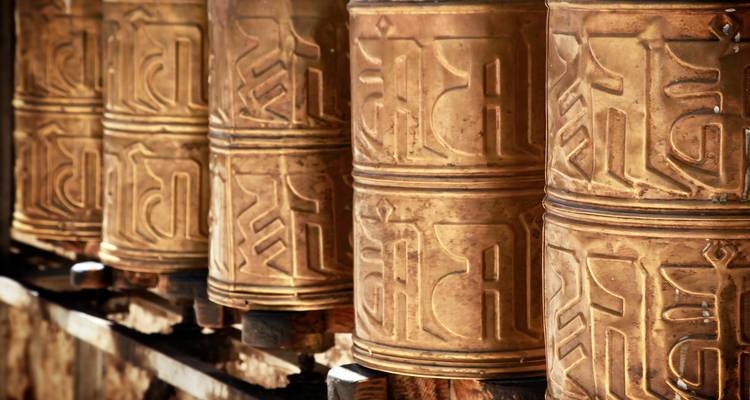 Reihe von kunstvollen goldenen tibetischen Gebetsrädern mit erhabener Schrift und patinierter Oberfläche.