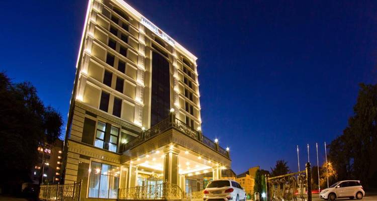 Extérieur d'hôtel la nuit avec façade illuminée.