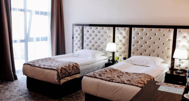 Chambre avec lits jumeaux et grandes fenêtres, décorée dans des tons neutres.