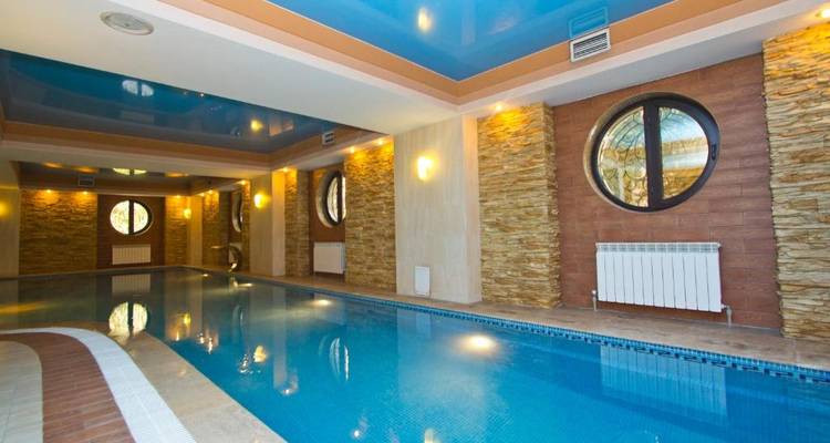 Piscine intérieure avec un plafond décoratif et des murs en pierre.