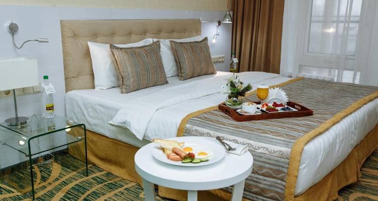 Chambre d'hôtel avec un lit fait et un plateau de petit-déjeuner sur le côté.