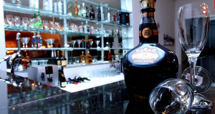 Barbereich mit einer Alkoholflasche und Gläsern im Fokus.