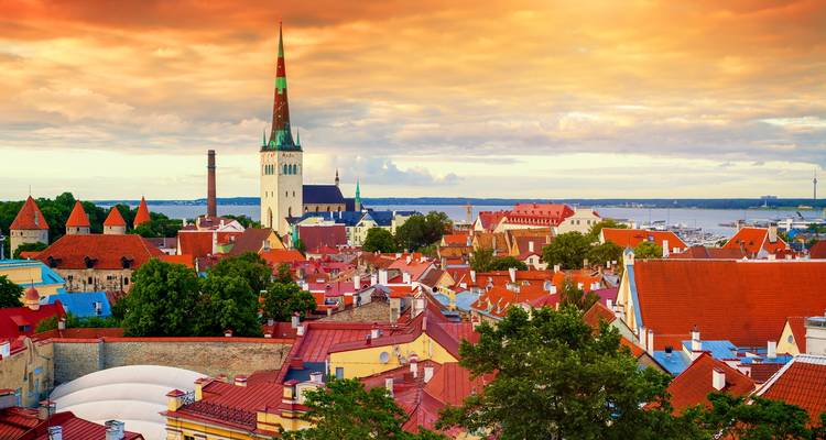 Tallinn cityscape with historical buildings under a dramatic sunset sky.