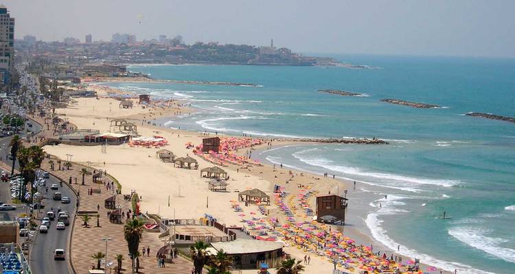 Beachfront with umbrellas and people enjoying the sea.
