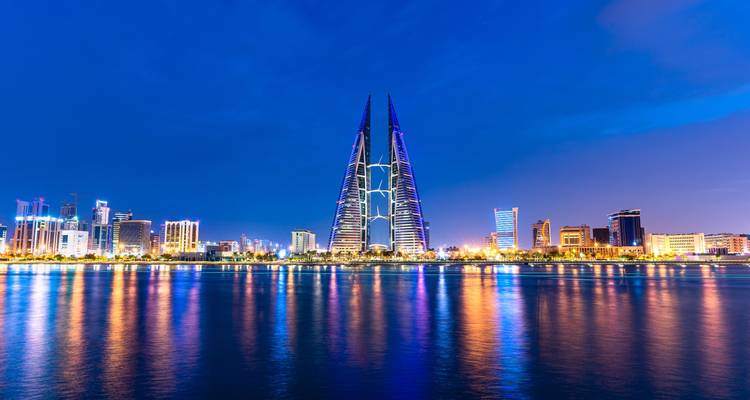 Horizonte de Manama por la noche con reflejos en el agua.