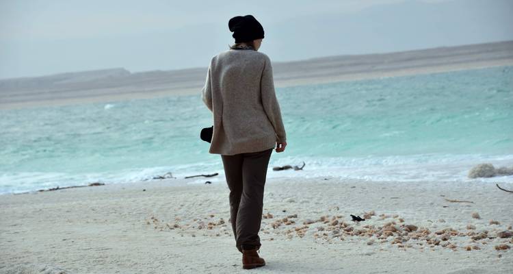 Persona caminando por una playa de sal con agua azul.