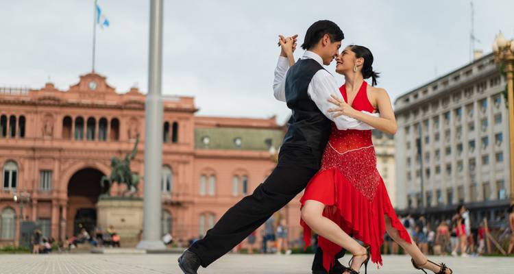 Danseurs de tango sur une place avec un bâtiment historique.