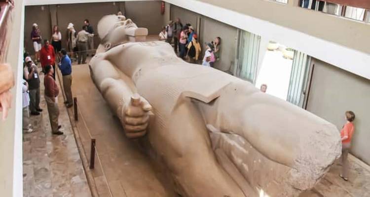 Massive umgestürzte Statue des Ramses II, horizontal im Memphis-Museum ausgestellt, mit Touristen in der Umgebung.
