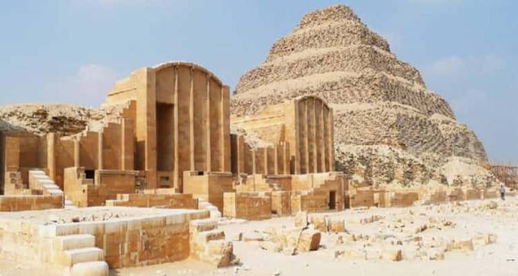 Ruinierter Innenhof und Kolonnaden, die zur Stufenpyramide des Djoser in der Nekropole von Sakkara unter diesigem Tageslicht führen.