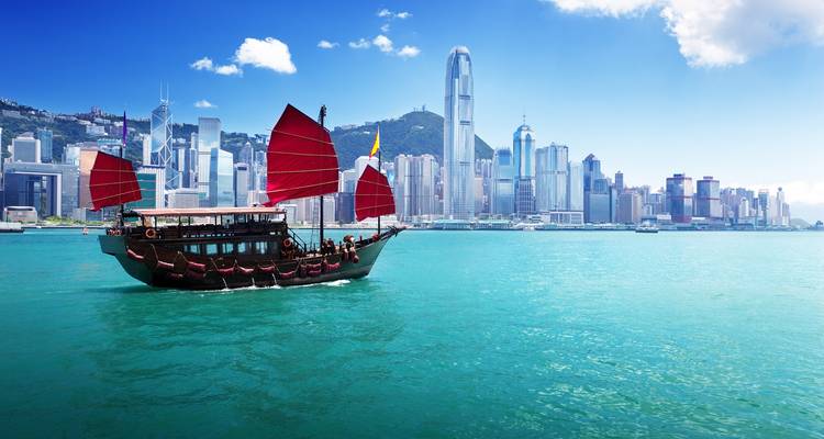 Traditional junk boat in Victoria Harbour with modern skyline.