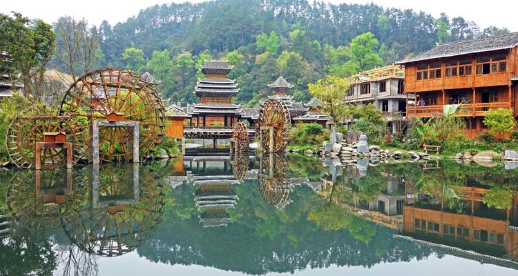 Estructuras icónicas de madera y ruedas hidráulicas junto a un lago.