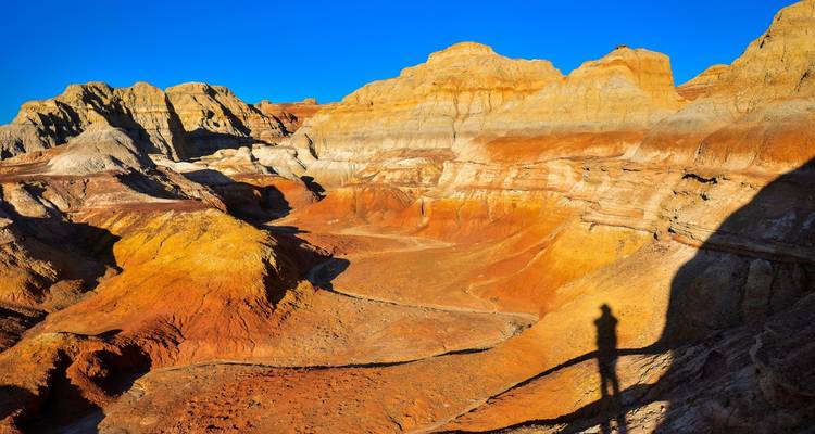 Paisaje rocoso colorido en capas con una silueta humana.