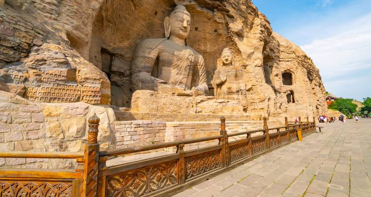 Buddhist sculptures carved into cliff face at a heritage site.