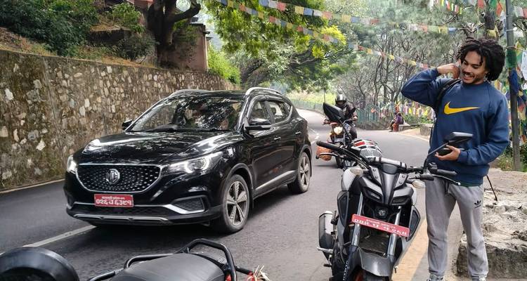 Person near motorcycles on a road with prayer flags.