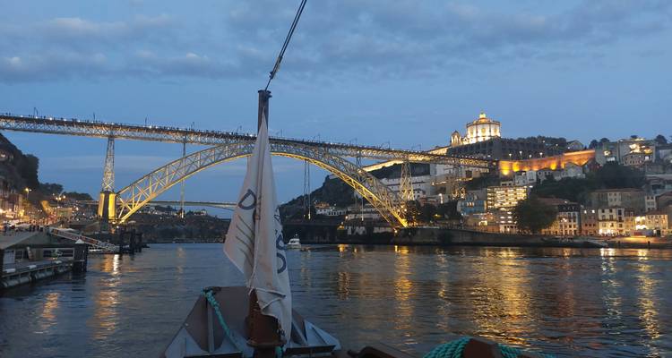 Abendliche Aussicht auf die Dom Luís I Brücke, die sich über den Douro erstreckt, mit funkelnden Lichtern der Portoer Hügel.