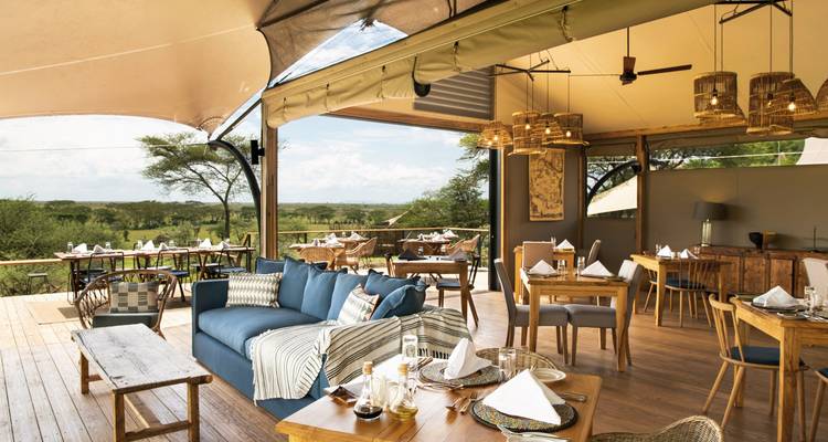 Openlucht eetruimte met elegante inrichting en uitzicht op de Afrikaanse savanne.