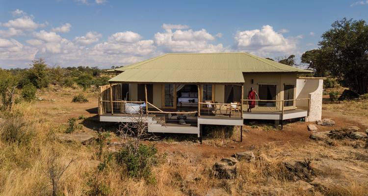 Huis in lodge-stijl met een terras in een savanne-omgeving.