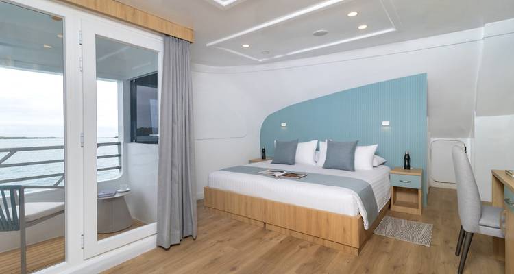 Modern ensuite cabin with king bed, sea-view balcony and light wood finishes.