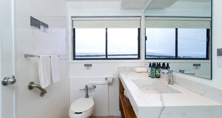 Bright yacht bathroom with marble countertop and large windows overlooking the sea.