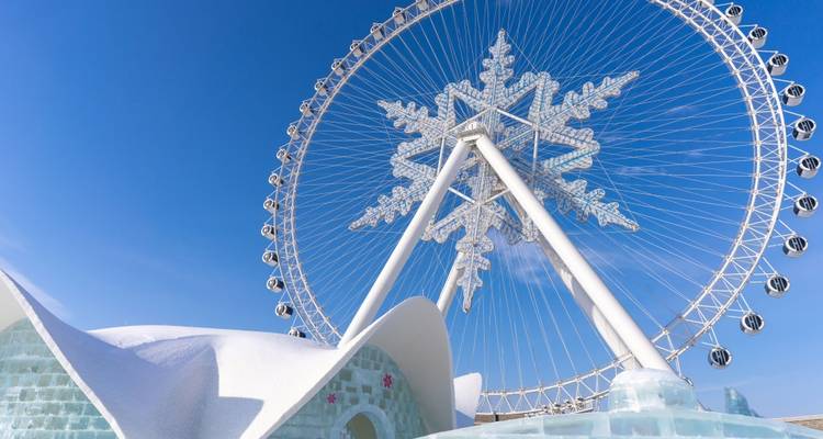 Sneeuwvlok reuzenrad en ijsstructuren onder een heldere blauwe hemel.