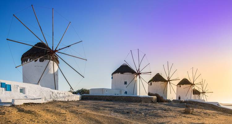 Moulins à vent traditionnels sur une colline avec un ciel dégagé au coucher du soleil.