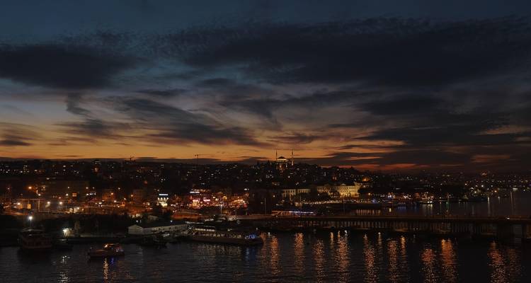 Une scène portuaire urbaine au crépuscule avec des lumières de ville éclatantes.