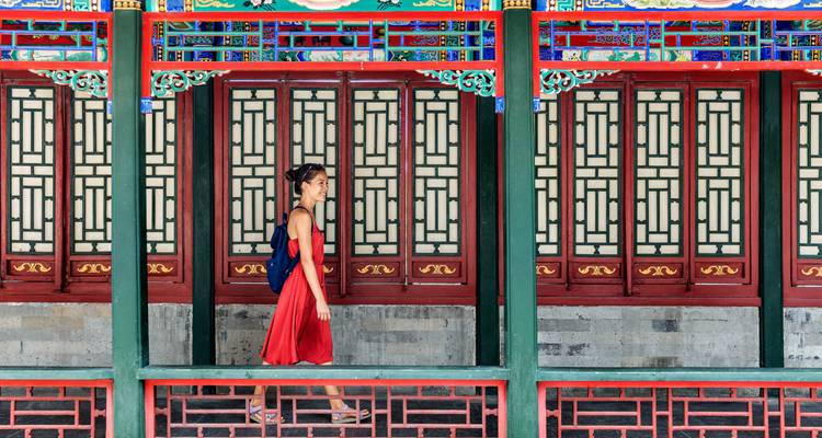 Persona caminando junto a una hilera de arquitectura china tradicional.