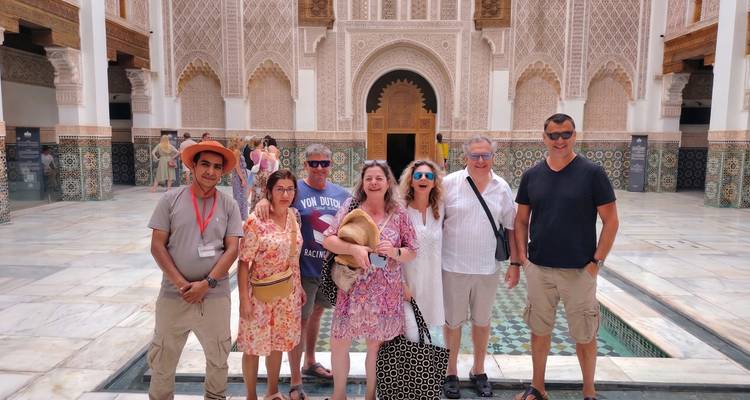 Group photo in ornate Moroccan courtyard with zellij tiles and carved arches.