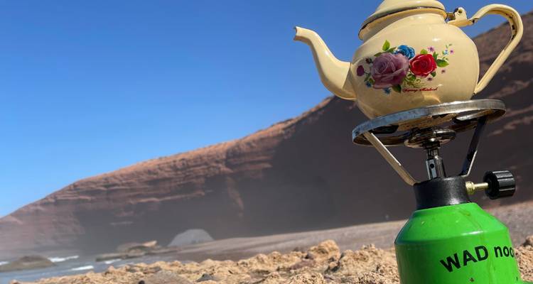 Théière sur une cuisinière avec un paysage rocheux en arrière-plan.