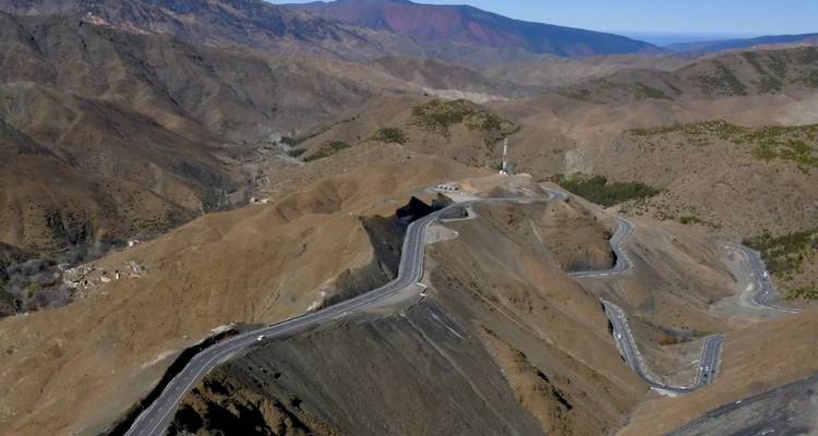 Kronkelende bergweg met omliggend landschap.