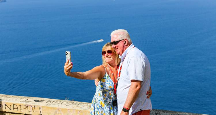 A couple taking a selfie with a blue sea backdrop.