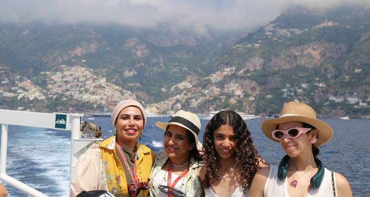 Four people posing on a boat with coastal backdrop.