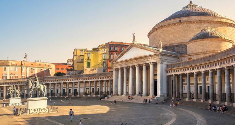 Grande Piazza del Plebiscito with neoclassical colonnade and domed basilica bathed in warm evening light.
