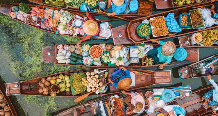 Drukke drijvende markt met verkopers in boten die kleurrijke producten verkopen.