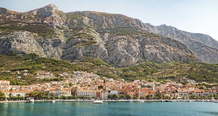 Ville côtière au pied de falaises rocheuses imposantes.