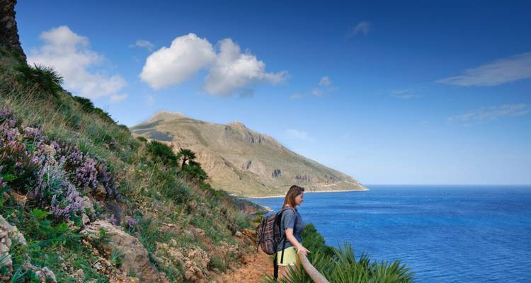 Einzelwanderer mit Rucksack bewundert die raue Küstenlinie und das kristallklare blaue Meer Westsiziliens
