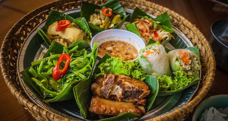 Assortiment de nourriture traditionnelle cambodgienne dans un panier avec des feuilles de bananier.