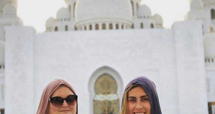 Deux femmes devant une grande mosquée blanche.