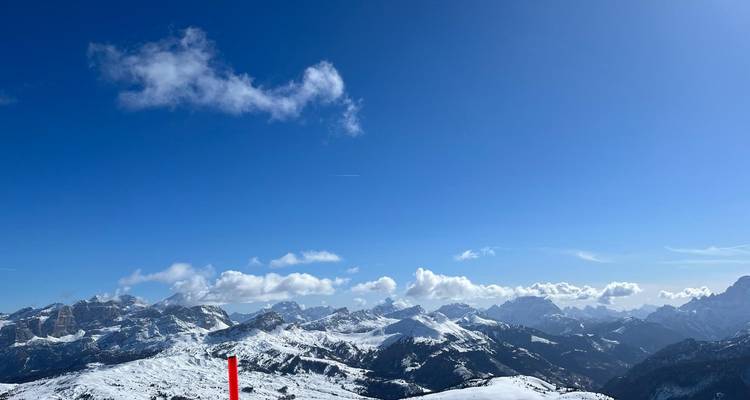 Vue large de montagnes avec un premier plan enneigé.