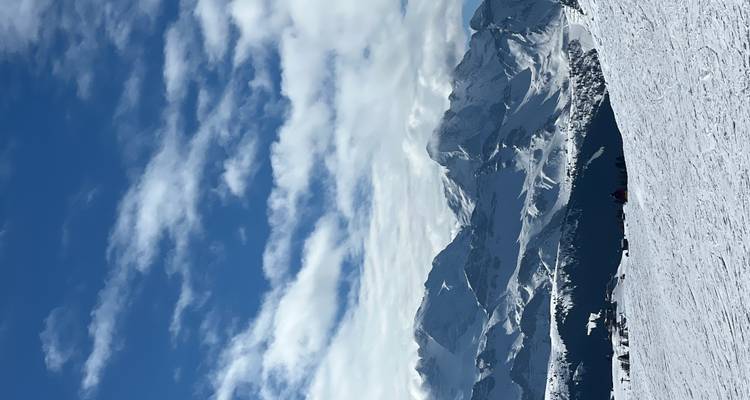 Des montagnes enneigées sous un ciel partiellement nuageux.