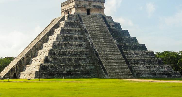 Une grande pyramide de pierre entourée d'herbe verte.