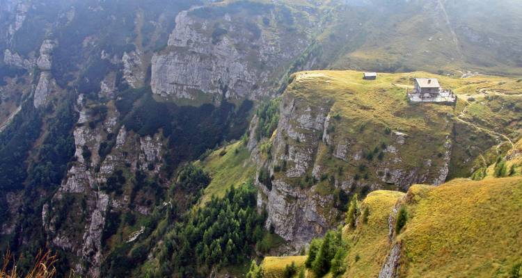 Falaise avec bâtiment au bord et forêt en contrebas.