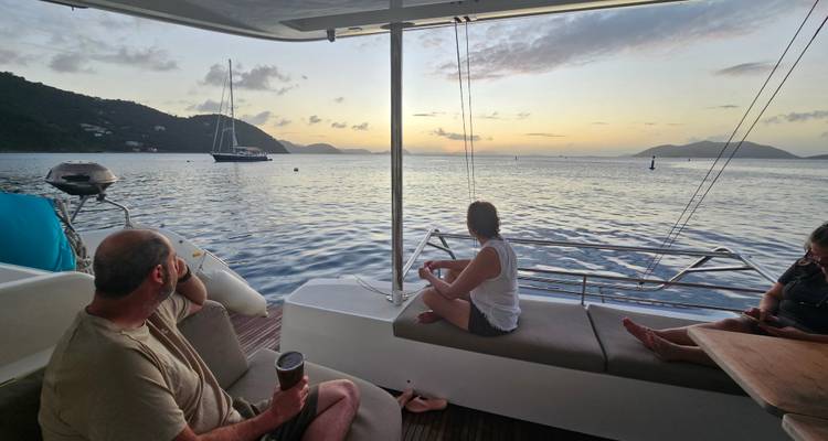 People relaxing on a boat, viewing sunset over the water.