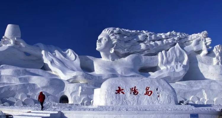 Grande sculpture de neige avec une personne qui marche à côté.