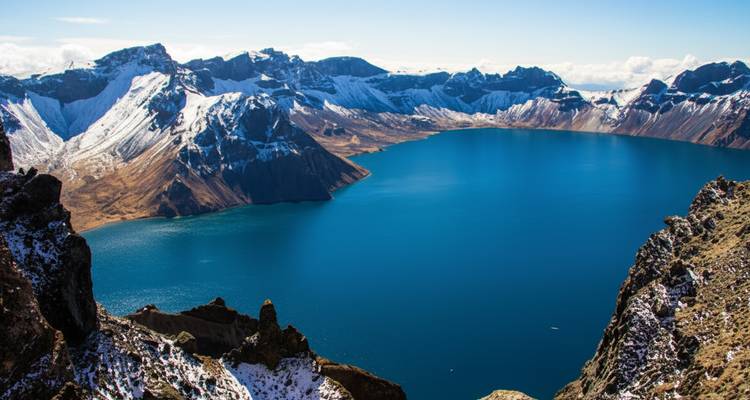 Lac d'eau bleue entouré de montagnes enneigées.