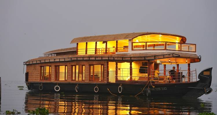 Illuminated houseboat on calm water during evening.