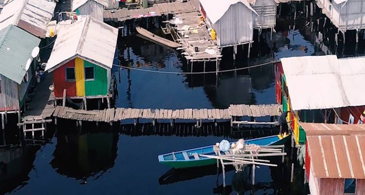 Maisons colorées sur pilotis et bateaux sur l'eau.