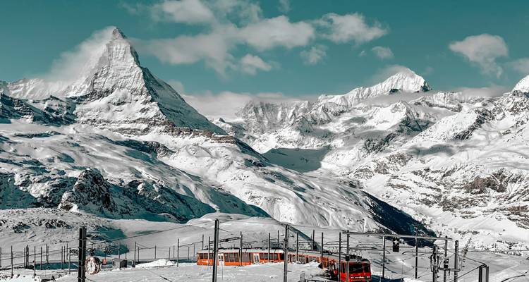 Snowy landscape with the Matterhorn and a red train.