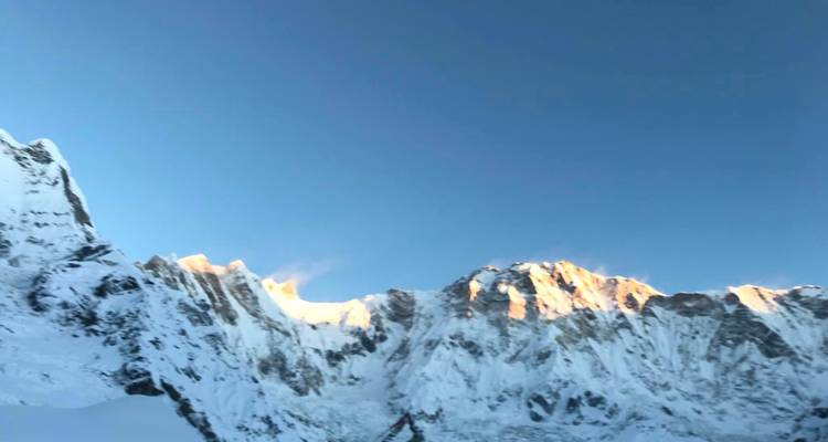 Panorama de montagnes enneigées avec un ciel bleu clair.