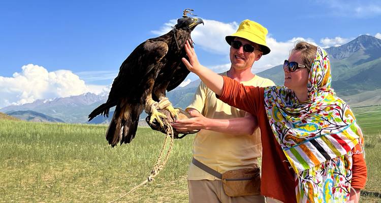Touristes interagissant avec un aigle tenu par un habitant local.